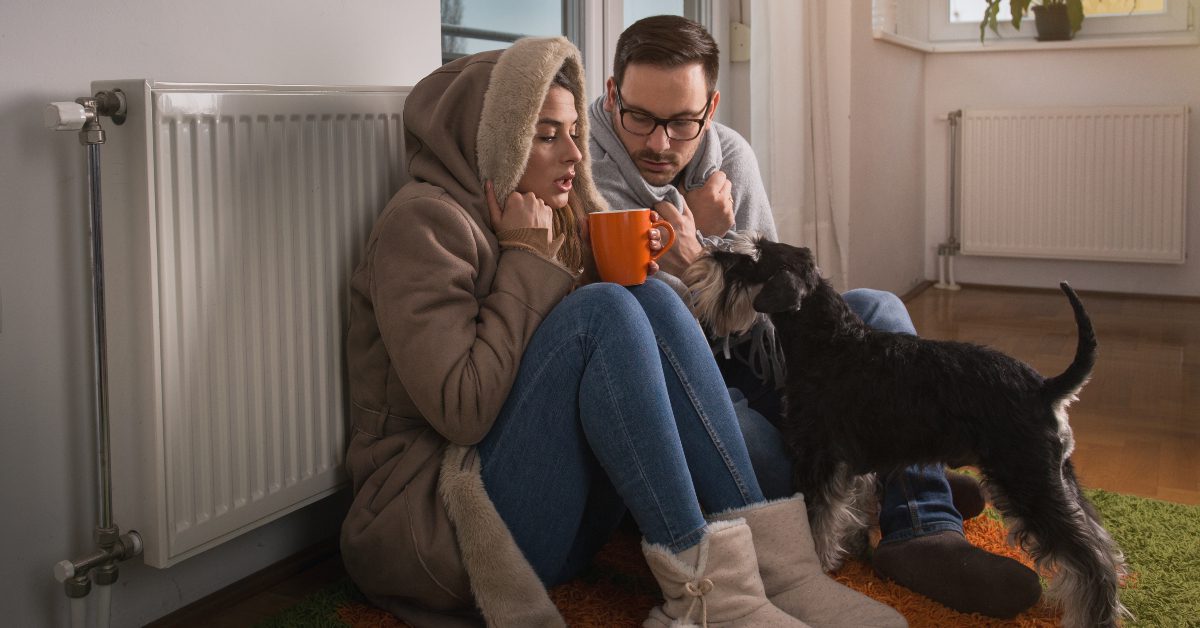Couple with dog shivering next to radiator